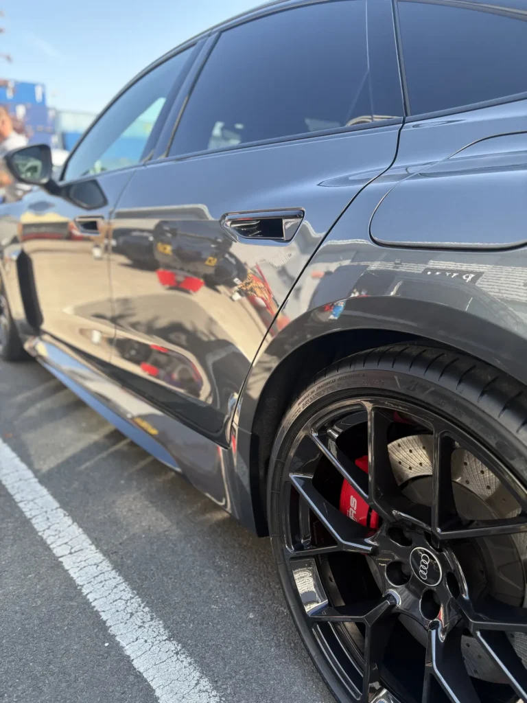 Reflections along a grey Audi estate with black wheels and red brake calipers