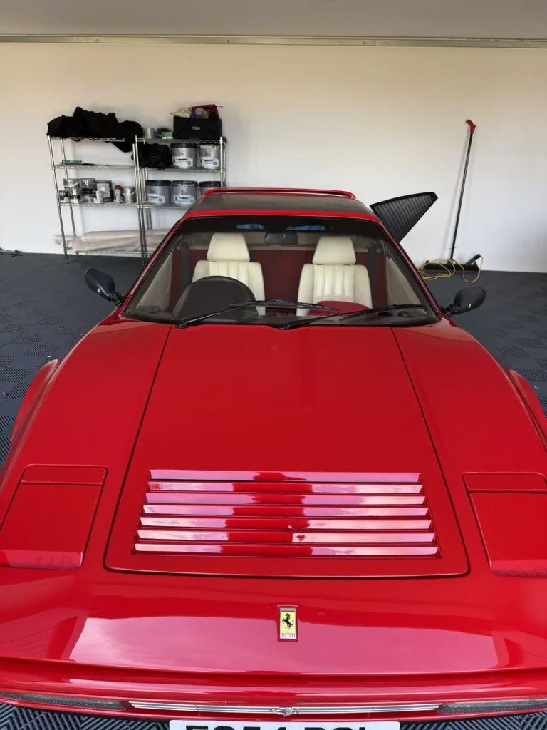 Red Ferrari 328 GTS viewed from the front inside a garage