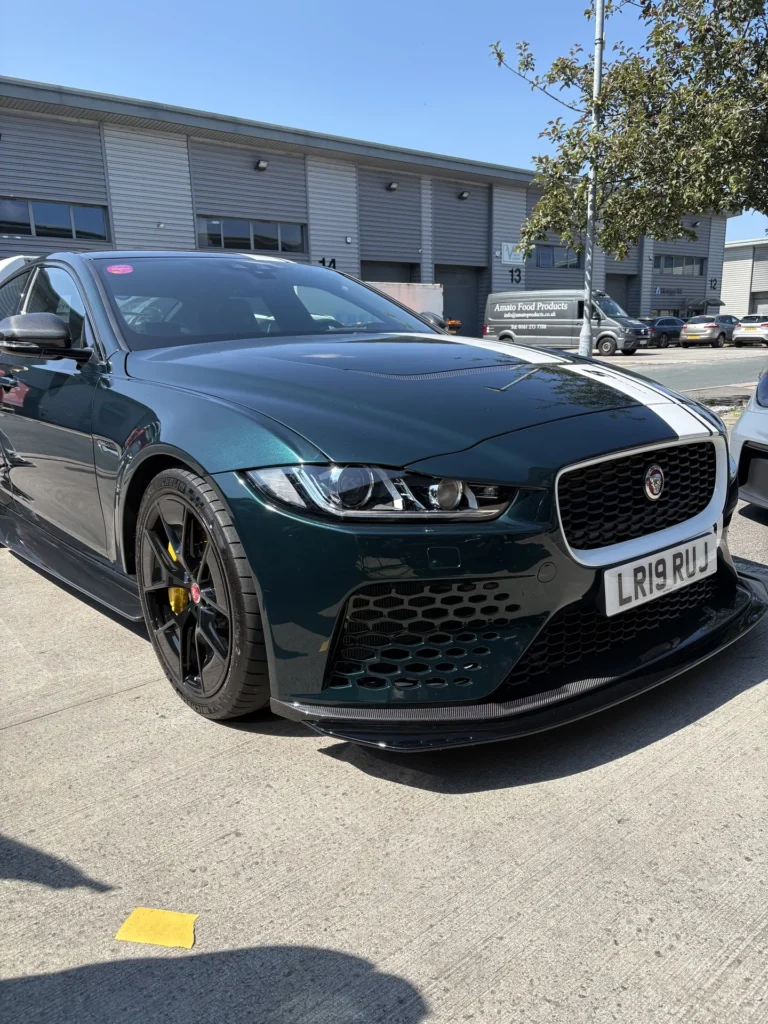 Dark green Jaguar saloon viewed from the front outside industrial units