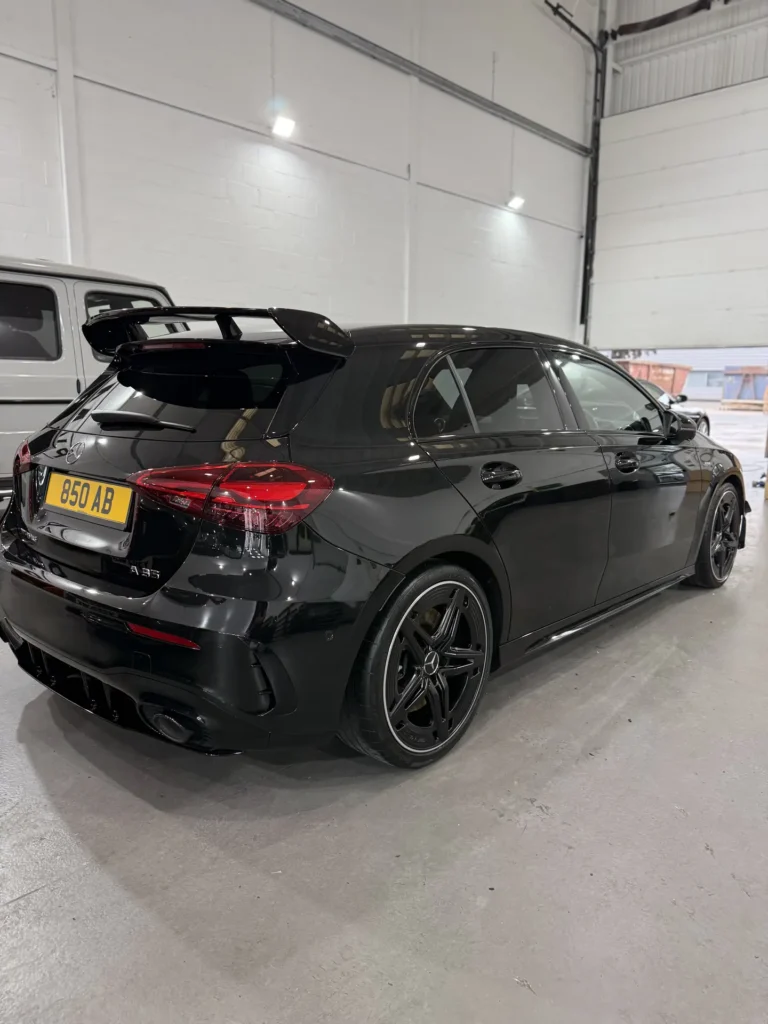 Black Mercedes-AMG hatchback viewed from the rear inside the workshop