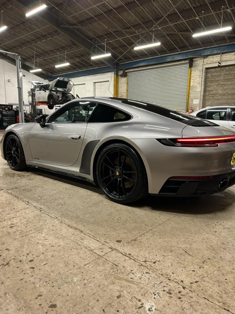 Silver Porsche 911 GTS, rear three-quarter view in a workshop